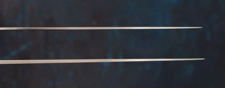 We see the tops of two knife blades: on top, a thin spine, and on bottom, a thicker one.